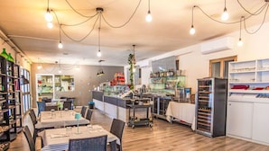 Um restaurante com piso de madeira, mesas com cadeiras, um balcão e prateleiras com garrafas.