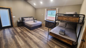 Quarto com duas camas, janela com cortinas, piso de madeira e iluminação embutida no teto.