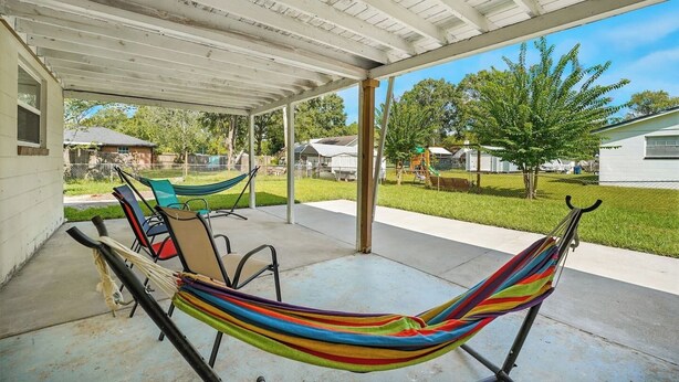 A covered patio with a hammock, chairs, and a concrete floor. - Spacious 3BR Home w/ Kitchen, Backyard & Parking (Baldwin)