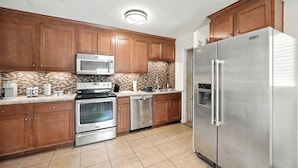 A kitchen with wooden cabinets, stainless steel appliances, and a tiled backsplash. - Spacious 3BR Home w/ Kitchen, Backyard & Parking (Baldwin)