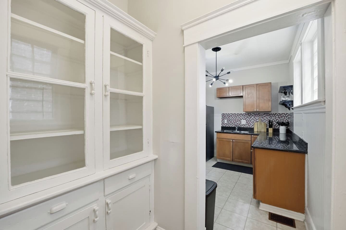 Una cocina con armarios de madera, encimera negra y salpicadero de azulejos.