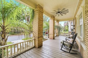 A covered porch with wooden flooring, brick pillars, and a ceiling fan. - Charming Duplex unit - Sleeps 8 w/ Full kitchen (Jacksonville)