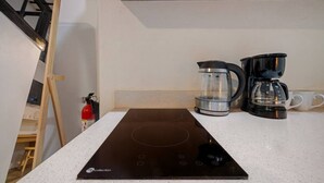 A kitchen with a black induction cooktop, a coffee maker, and a glass carafe. - Il Rifugio Nascosto | Somewhere In Heaven (San Juan)