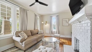 Ein Wohnzimmer mit einer Couch, einem runden Couchtisch, einem Kamin und einem Deckenventilator.