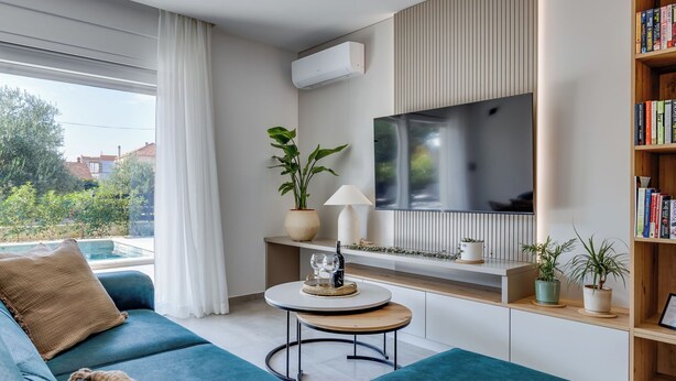 Moderni olohuone, jossa on sininen sohva, pyöreä sohvapöytä, televisio ja kirjahylly.