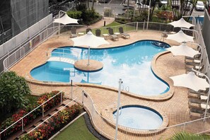 Ein Poolbereich mit verschiedenen Schwimmzonen, Liegestühlen und einem umgebenden Zaun.