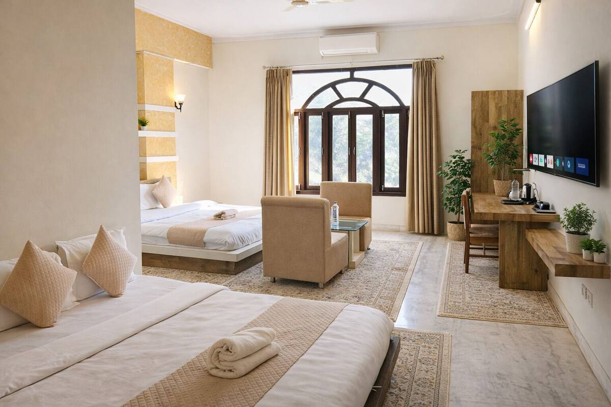 A hotel room with a bed, a sofa, a desk, a TV, and a window with curtains.