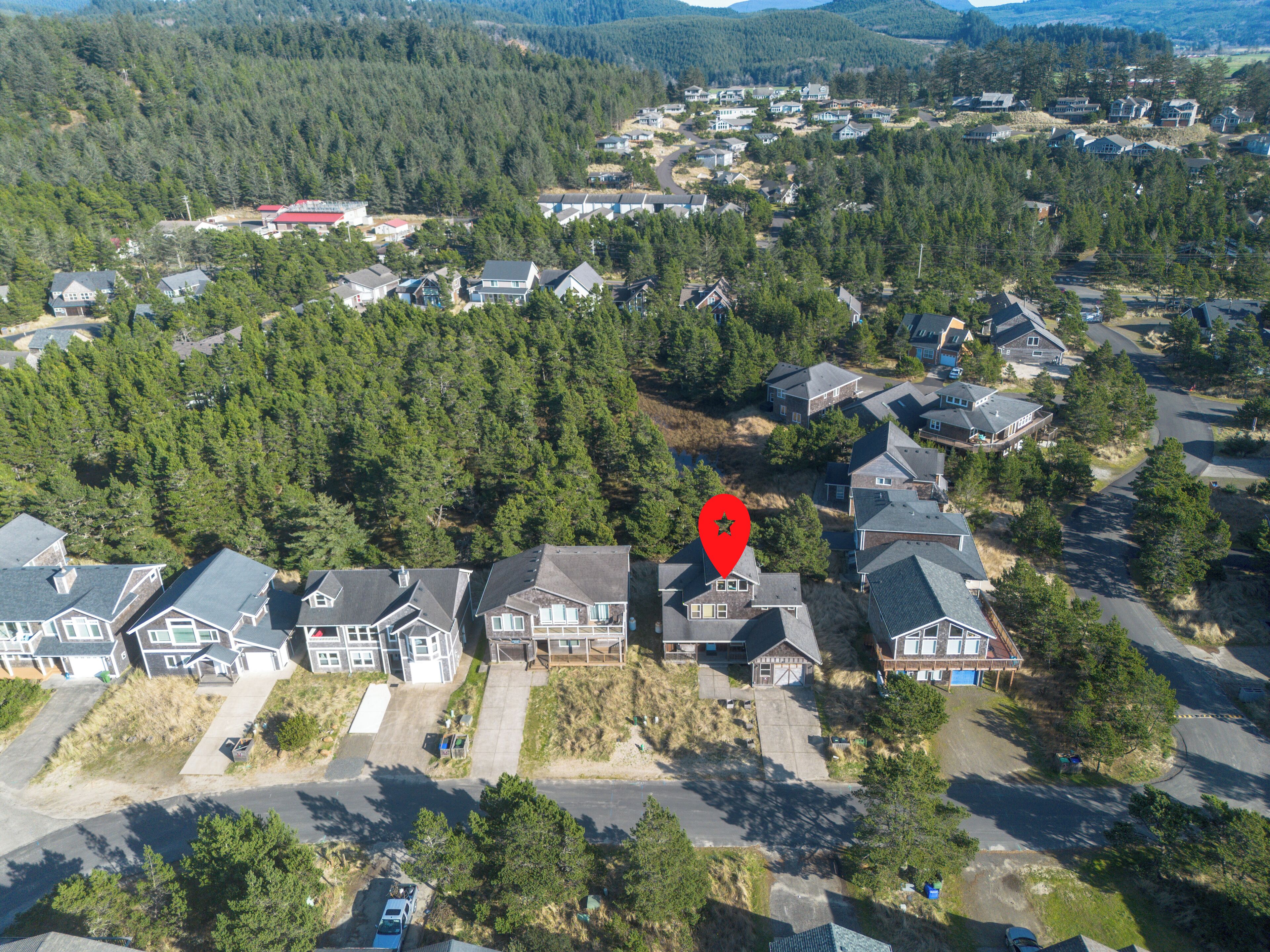 An aerial view of a residential area with houses, roads, and surrounding forest.