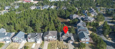 An aerial view of a residential area with houses, roads, and surrounding forest.