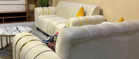 A living room with a beige sofa set, a coffee table, and a TV against the wall.