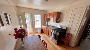 A kitchen with wooden cabinets, a stove, and a dining table with chairs. - Babich Building - 3 Bedroom - Upper Apt #4 (West Allis)