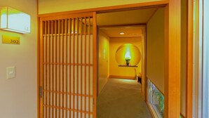 A hallway with a traditional Japanese sliding door, a number sign '302', and a lit lamp on a shelf. - ATAMI KAKUREZATO (Atami)