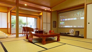 A traditional Japanese room with tatami flooring, a low wooden table, and a projector screen displaying a presentation. - ATAMI KAKUREZATO (Atami)