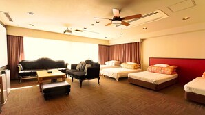 A hotel room with a sofa, two single beds, a small table, and a ceiling fan. - ATAMI KAKUREZATO (Atami)