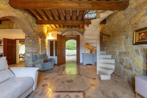 A stone-walled interior with a wooden ceiling, a staircase, and a seating area with a sofa and armchairs. - Fontana 1 - Holiday Rental with swimming pool on the Tuscan Coastline (Monteverdi Marittimo)