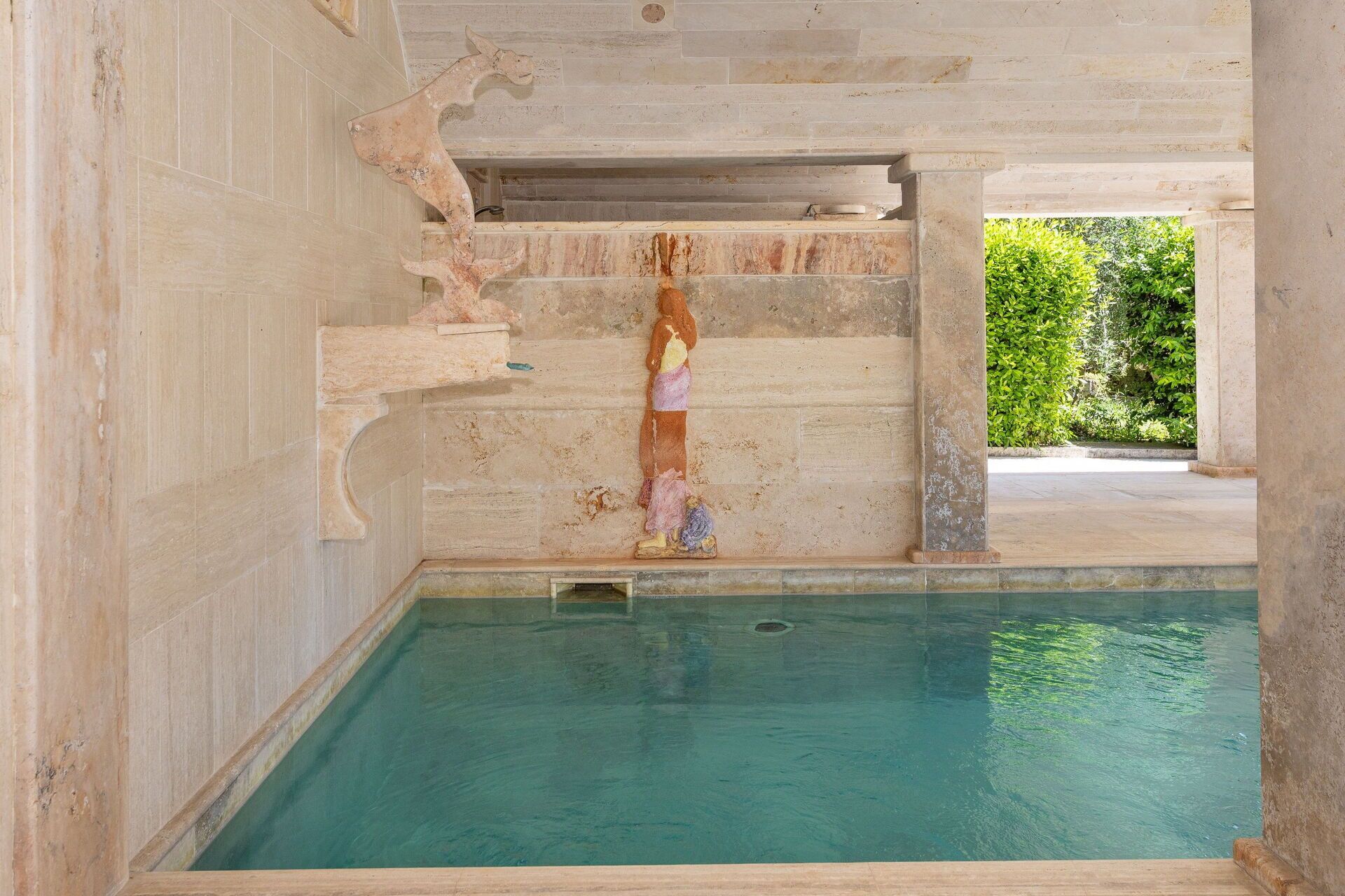 Piscina con paredes de piedra y vistas a la vegetación.