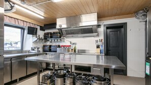 A modern kitchen with stainless steel appliances, a large island, and a window overlooking a mountainous area. - Charming Alpine guesthouse for 23 people (Hollersbach im Pinzgau)
