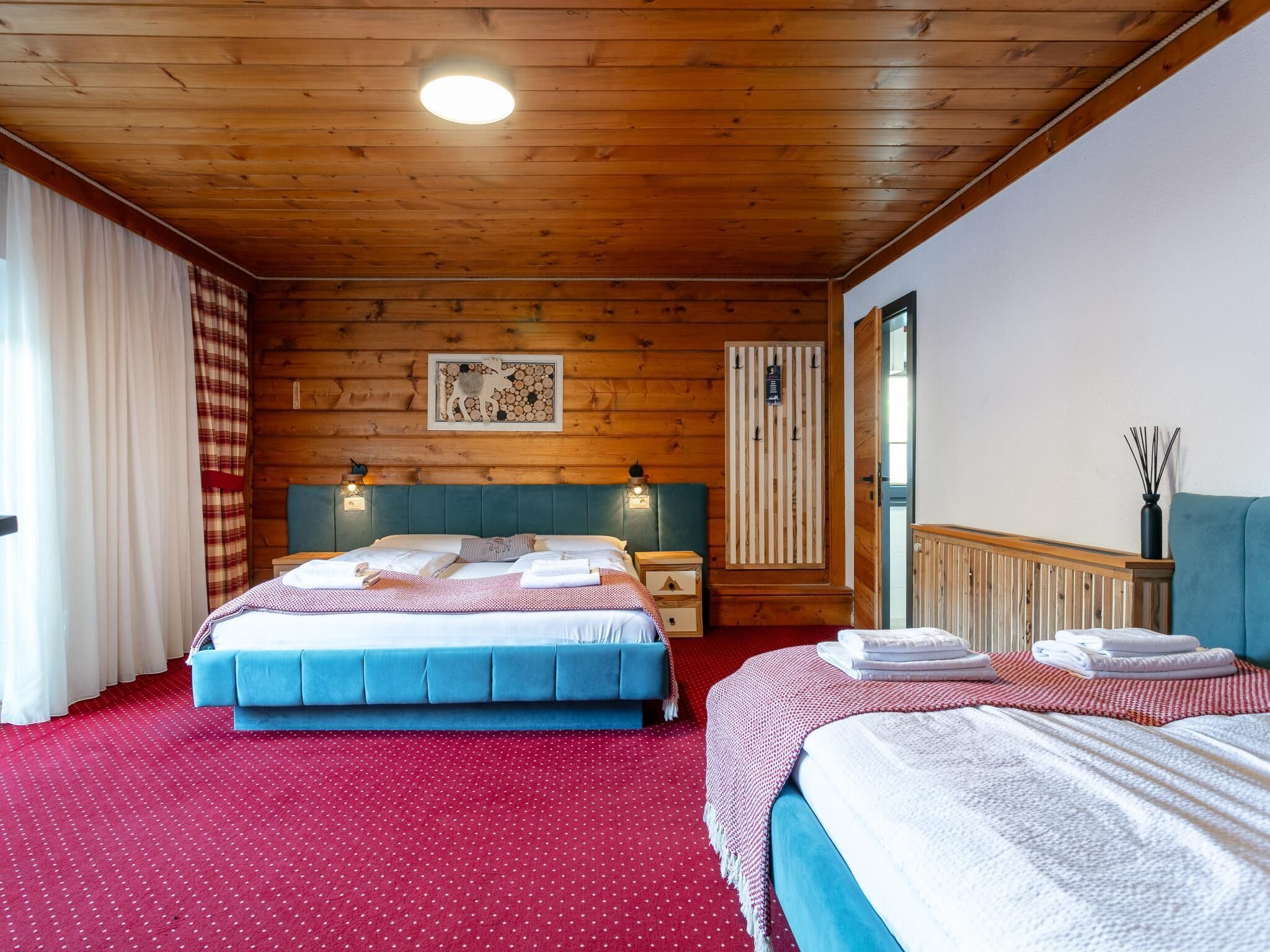 Une chambre avec deux lits, un plafond en bois et une moquette rouge.