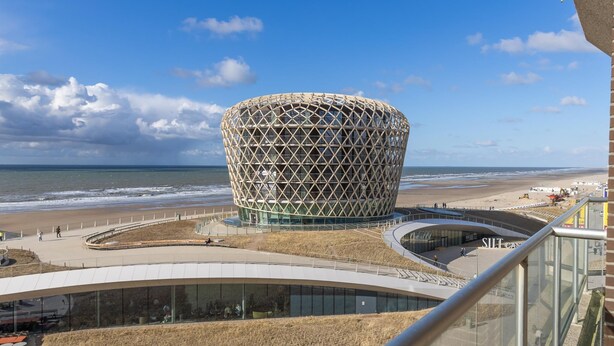 A modern building with a unique spherical design, located near a beach with a clear sky. - Apartment on the 6th floor with sea view (Middelkerke)