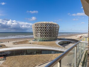 Ein modernes Gebäude mit einem markanten, kugelförmigen Design in Strandnähe, vor blauem Himmel.