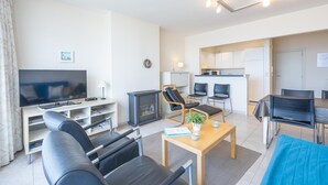 Ett modernt vardagsrum med en platt-TV, en öppen spis och en matplats med bord och stolar.
