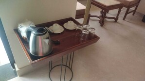 Una bandeja de madera con una tetera, tazas y vasos sobre una mesa.