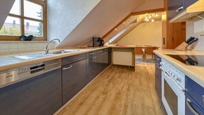 Una cucina moderna con soffitto spiovente, elettrodomestici integrati e una finestra che si affaccia su una zona residenziale.