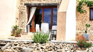 A stone building with a patio, a table, and chairs.