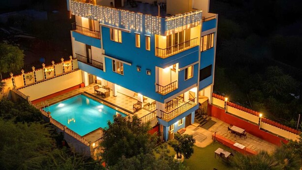 A multi-story building with a swimming pool, balconies, and string lights.
