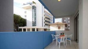 Ein Balkon mit Tisch und Stühlen, eine blaue Wand und ein Gebäude im Hintergrund.
