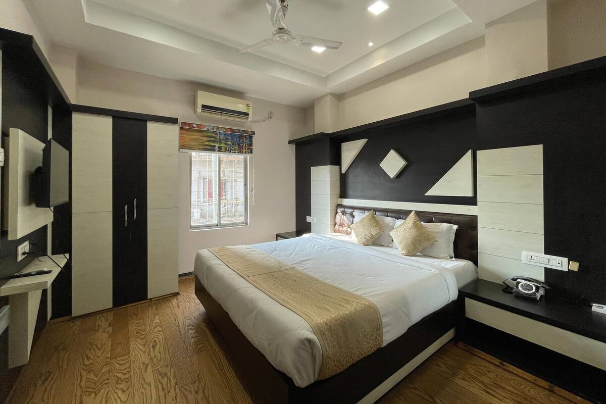 A bedroom with a bed, bedside tables, a wardrobe, a ceiling fan, and a window with a view of the outside.