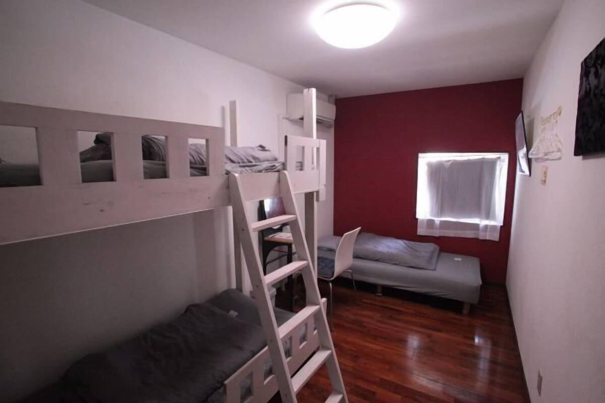 A room with bunk beds, a desk, a chair, and a window with curtains.