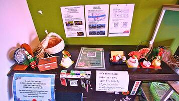 A counter with various informational posters, a QR code, and a sign instructing customers to place their keys in the checkout box.