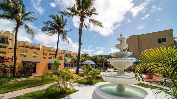 A multi-tiered fountain in a courtyard surrounded by palm trees and a hotel building. - Silent residence in downtown Sosua, you don't hear that every day! (Sosúa)
