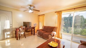 A living room with a sofa, a dining table with chairs, a TV, and a ceiling fan. - Silent residence in downtown Sosua, you don't hear that every day! (Sosúa)