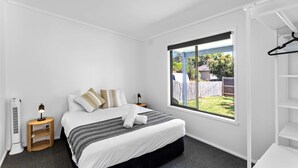 Ein Schlafzimmer mit Bett, Fenster, Heizung und Kleiderschrank.