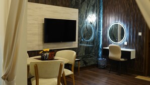 A modern room with a wooden floor, a flat-screen TV mounted on a wall, a round mirror, and a desk with a chair. - Hotel Rosevelt (Islamabad)