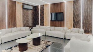 A modern living room with a sectional sofa, a coffee table, and a flat-screen TV mounted on the wall. - Hotel Rosevelt (Islamabad)