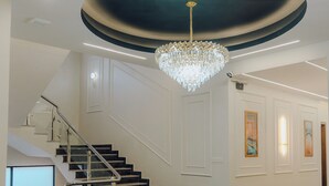 A spacious lobby with a grand staircase, a chandelier, and framed artwork on the walls. - Hotel Rosevelt (Islamabad)
