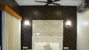 A modern bedroom with a large bed, a ceiling fan, and a marble headboard. - Hotel Rosevelt (Islamabad)