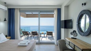 Una camera d'albergo con un letto, una televisione, una scrivania e vista mare.
