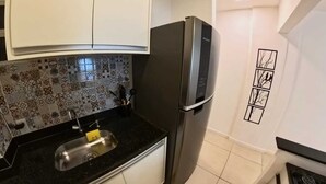 A kitchen with a black refrigerator, a sink with a yellow soap dispenser, and a tiled backsplash with various patterns. - Studio Safe & Modern • 5 min Ferry to Rio• 1Gbps Wi-Fi • Pet & Kid-Friendly (Niterói)