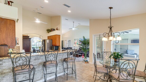 A spacious kitchen with a bar area, high ceilings, and modern lighting fixtures. - Beach Days & Fairways: Rotonda West Snowbird Home (Rotonda West)