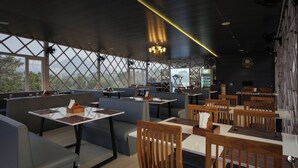 A restaurant with high ceilings, large windows, and a mix of seating arrangements including booths and tables. - The Forest Hills Resort (Sarada)