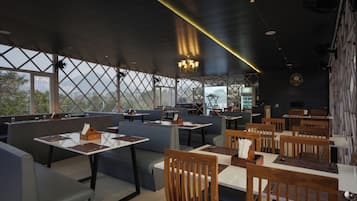 Un restaurante con techos altos, amplias ventanas y una variedad de opciones de asientos, incluyendo cabinas y mesas.