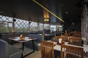 A restaurant with high ceilings, large windows, and a mix of seating arrangements including booths and tables. - The Forest Hills Resort (Sarada)