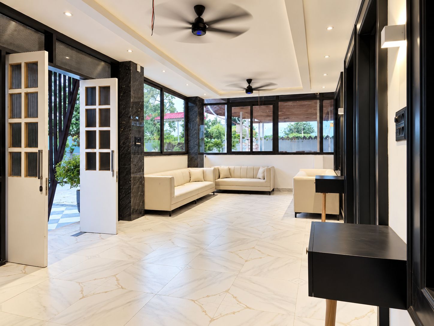 A modern hotel lobby with a beige sofa, a black table, and a ceiling fan.