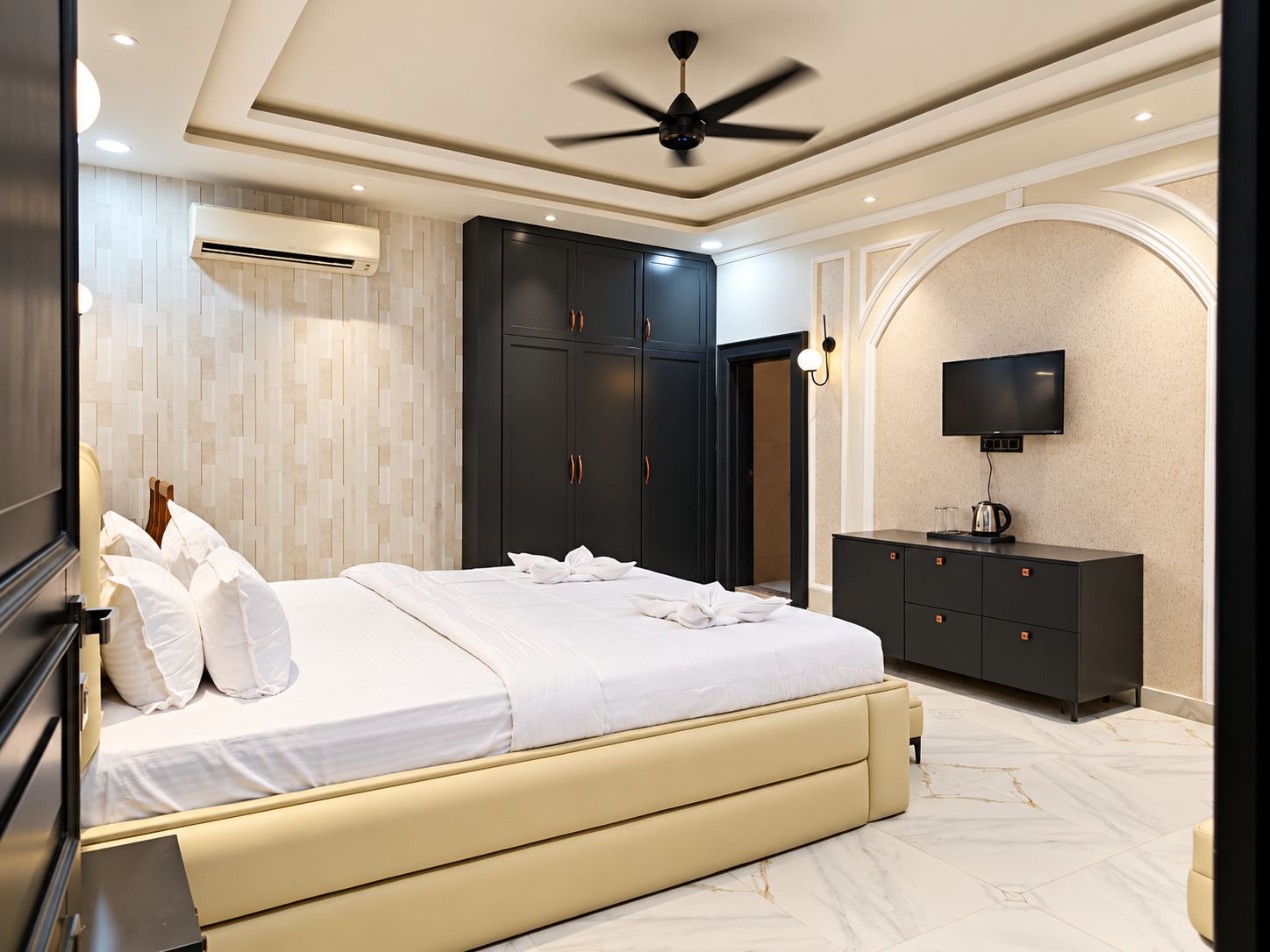 Un dormitorio moderno con cama, armario, televisión y ventilador de techo.