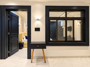 A modern interior with a dark wooden door, a black console table with a drawer, and a large window with a decorative grid pattern. - The Forest Hills Resort (Sarada)