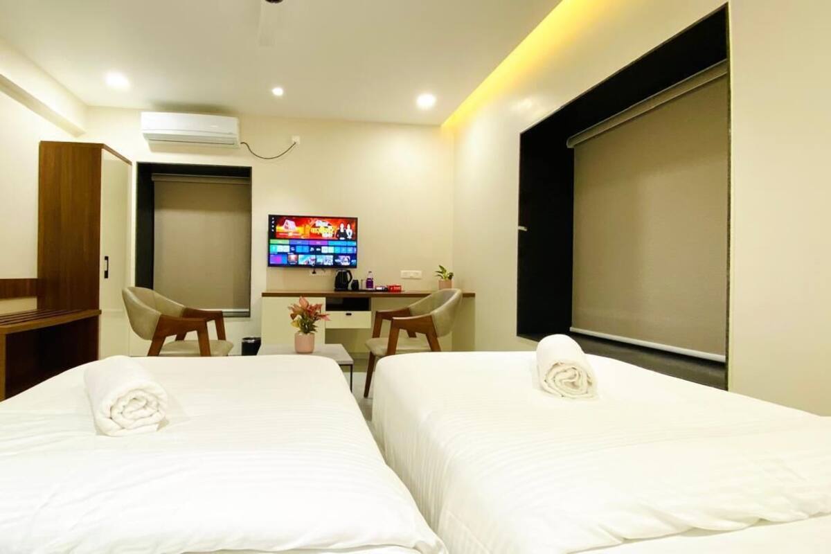 Camera d'albergo con due letti, una scrivania, una sedia, una televisione e un'ampia finestra.